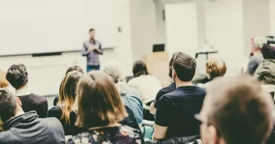 Profesor enseñando un temario en un aula con alumnos atendiendo