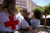 Una cuidadora de la Cruz Roja acompañando a personas mayores