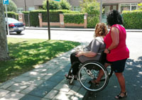 Una cuidadora atiende a una persona en silla de ruedas que lo necesita y que también puede aportar autonomía personal
