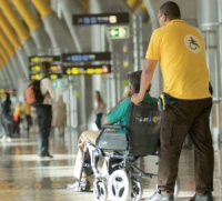 Personal de apoyo en aeropuerto empujando silla de ruedas, aena