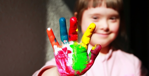 niña con síndrome de down sonriendo y con la mano pintada en el día del síndrome Down 2019
