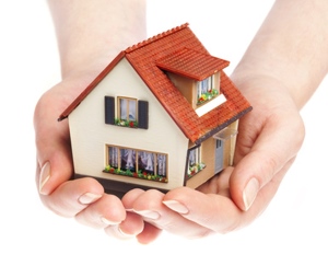 manos sosteniendo maqueta de una casa