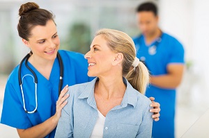 Mujer sonriendo y hablando con personal sanitario de azul