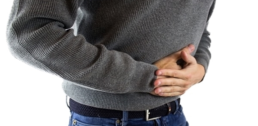Hombre llevándose las manos al estómago como señal de dolor - Día mundial contra el dolor neuropático