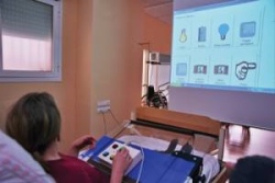 persona tendida en la cama gestionando mandos para acciones a través de una pantalla como productos de paoyo