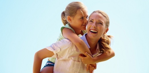 mujer sonriendo con niña cogida a su espalda