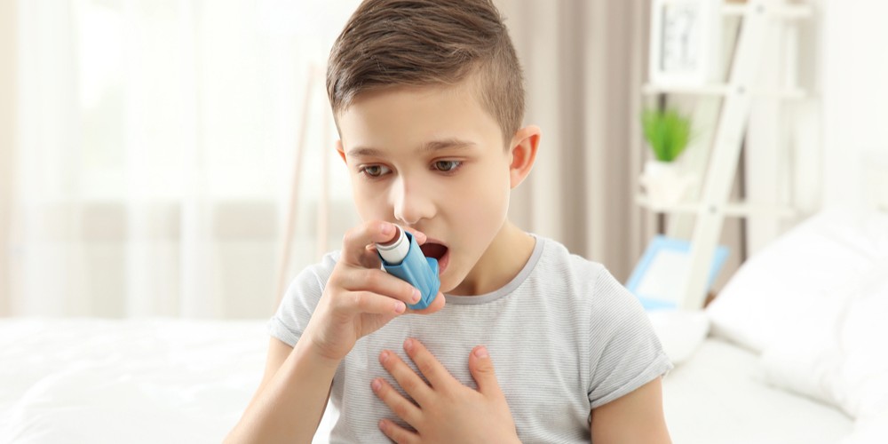 Un niño usando un inhalador durante un ataque asmático