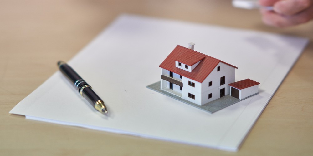 Ilustración de una carpeta con contratos dentro, una casa en pequeño encima y un bolígrafo, representando bienes patrimoniales