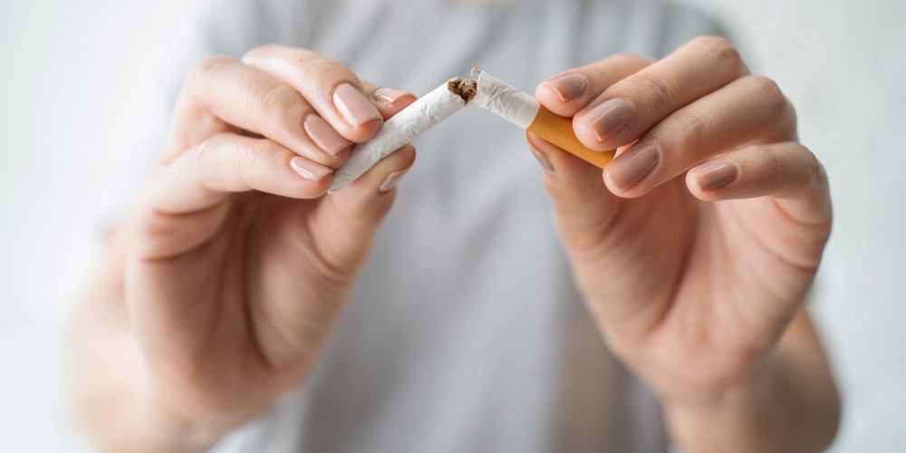 Manos de una mujer rompiendo un cigarro en dos
