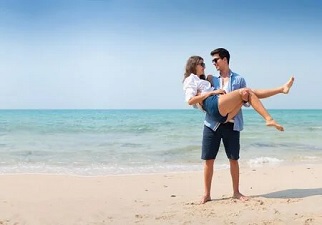 Una mujer en brazos de su pareja saliendo del mar