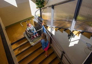 Niña sentada en un salva escalera y su madre en la escalera la mira