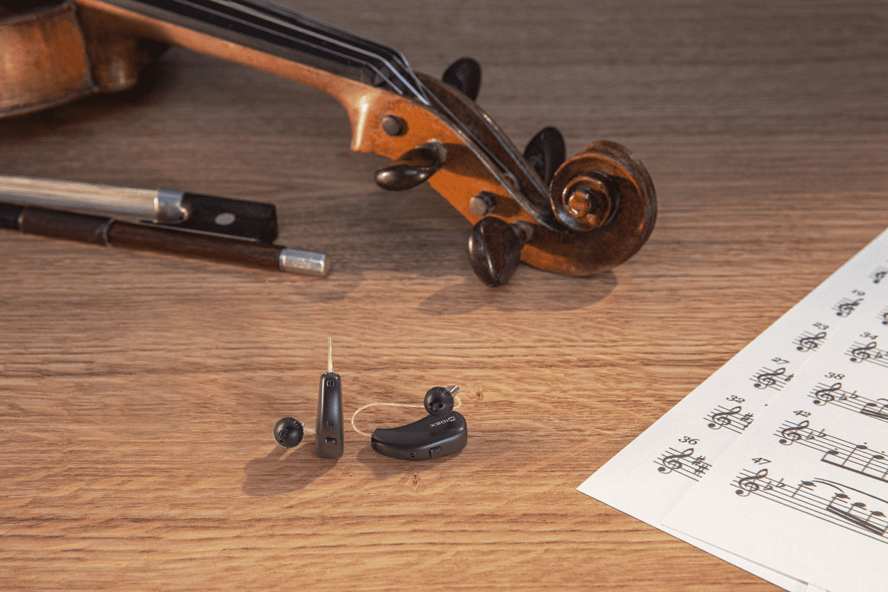 Fotografía de una mesa con una partitura, unos audífonos y un violín.