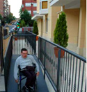Persona en silla de ruedas accede a edificio por rampa accesible