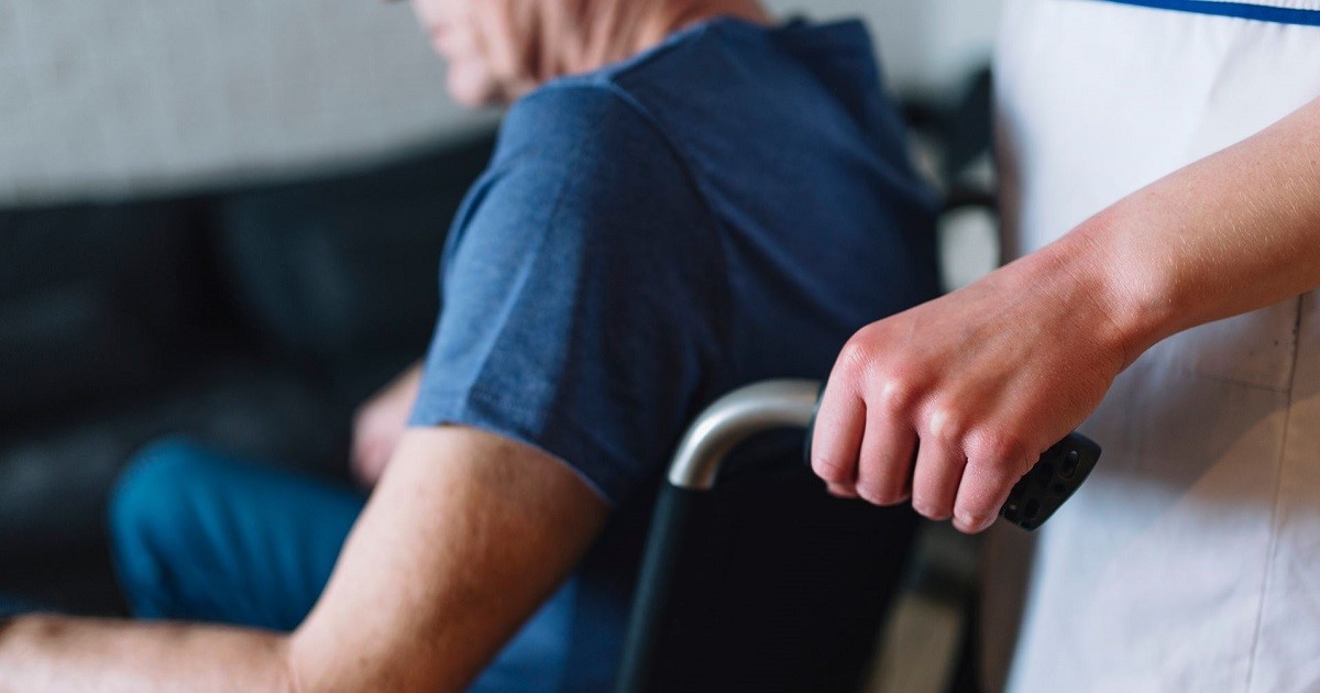 persona llevando en sillas de ruedas a una persona mayor en situación de dependencia. Baremos de valoración de la dependencia.