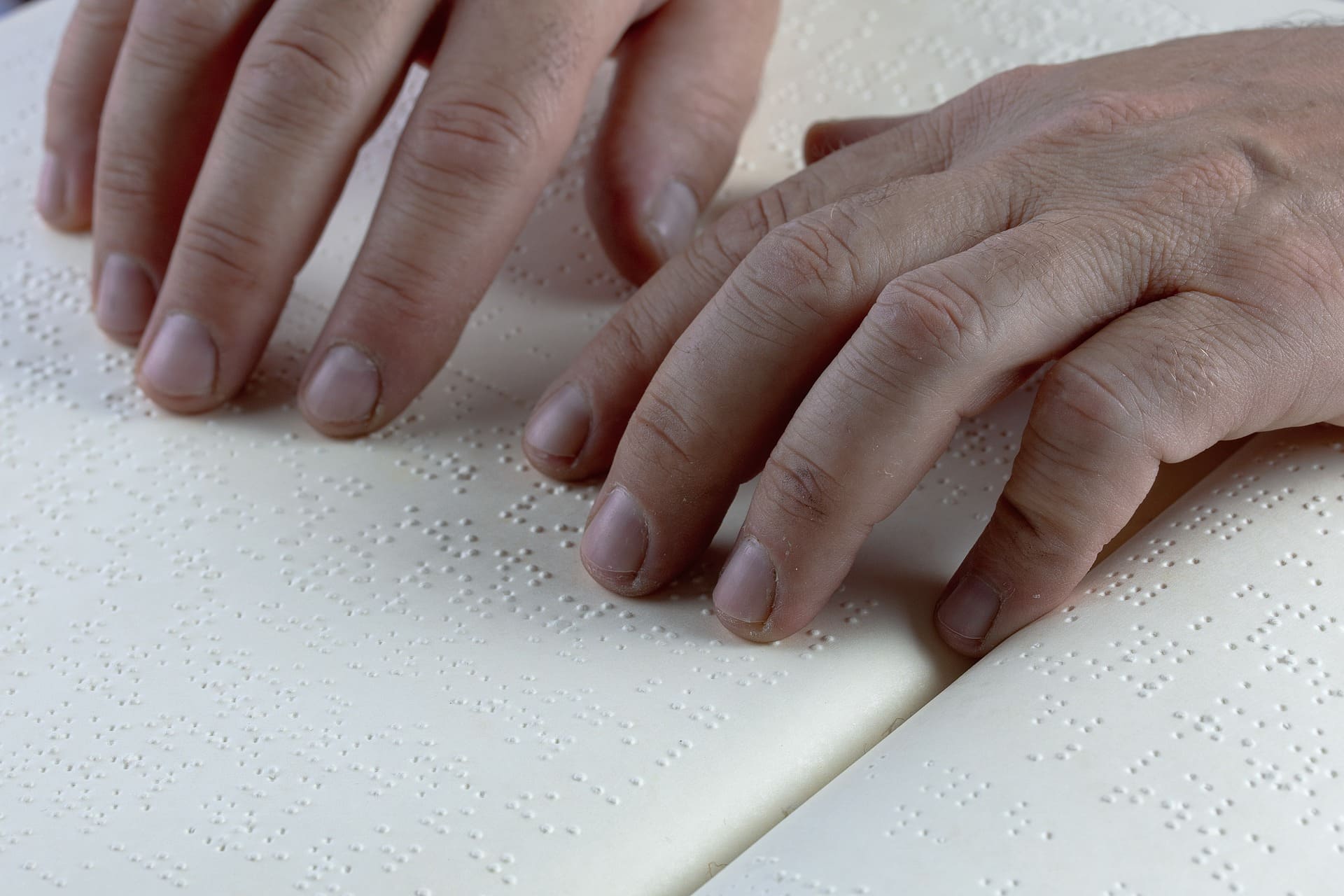 manos leyendo en un libro braille