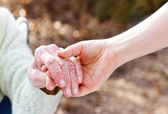 Una mano de el cuidador con la mano de una persona mayor