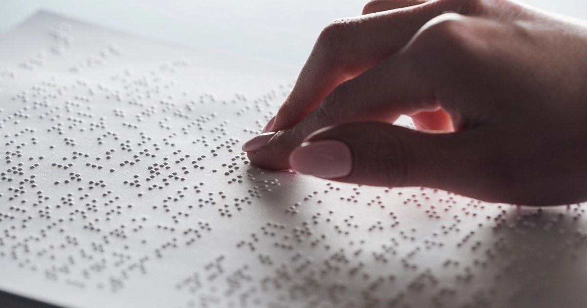 mano sobre un folio de pale con puntos Braille