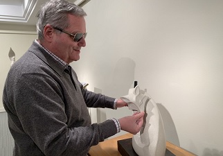 Una persona ciega toca la escultura Zorro Ártico de la exposición de Cortés