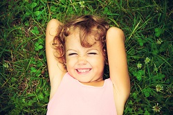niña tumbada y riendo en el campo