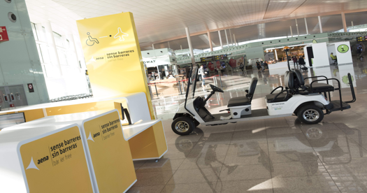 Punto de asistencia accesible en aeropuerto con monolito y vehículo adaptado.