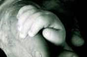 Mano de un niño cogiendo la mano de una persona mayor con Parkinson