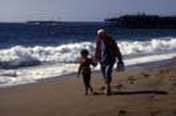 Un abuelo con Parkinson paseando por la arena de la playa con su nieto