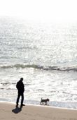Un hombre paseando por la playa con su perro
