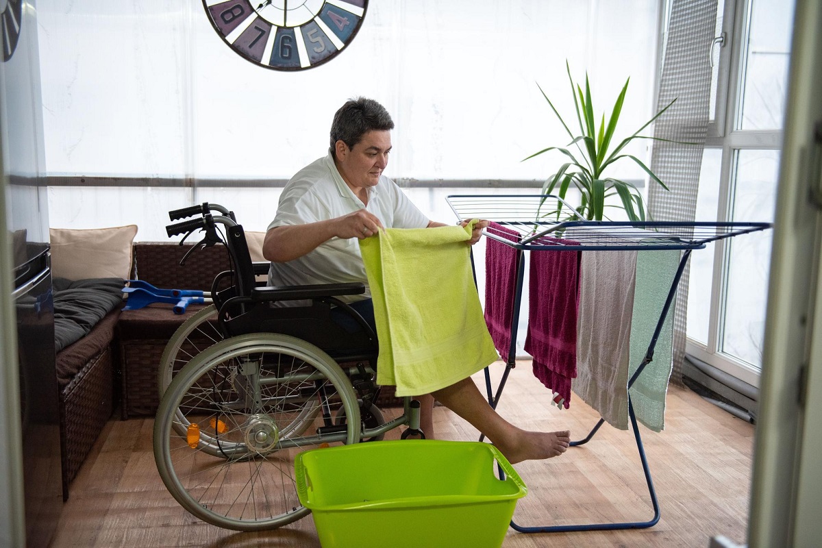persona con movilidad reducida tendiendo la ropa en un tendedero. Refleja una actividad de la vida diaria.