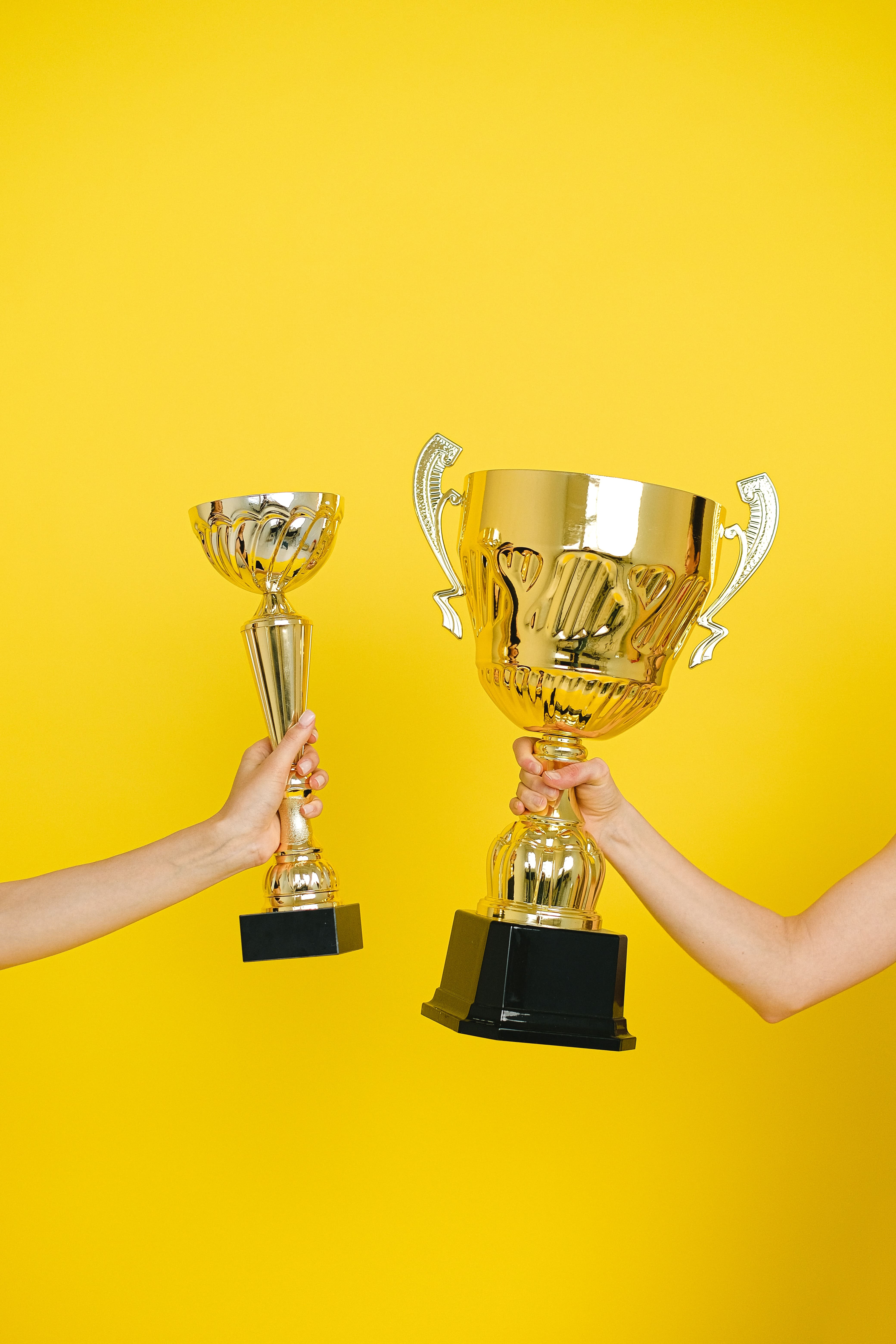 dos manos alzando dos copas de premios