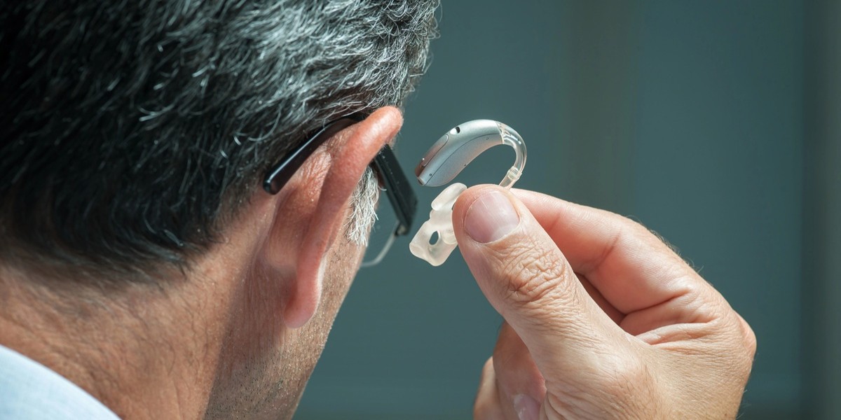 hombre colocándose un audífono