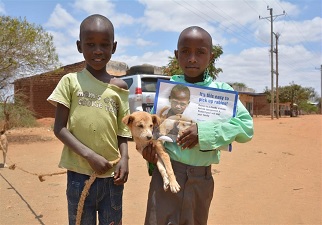 Dos niños africanos con un cachorro de perro haciendo propaganda contra la rabia