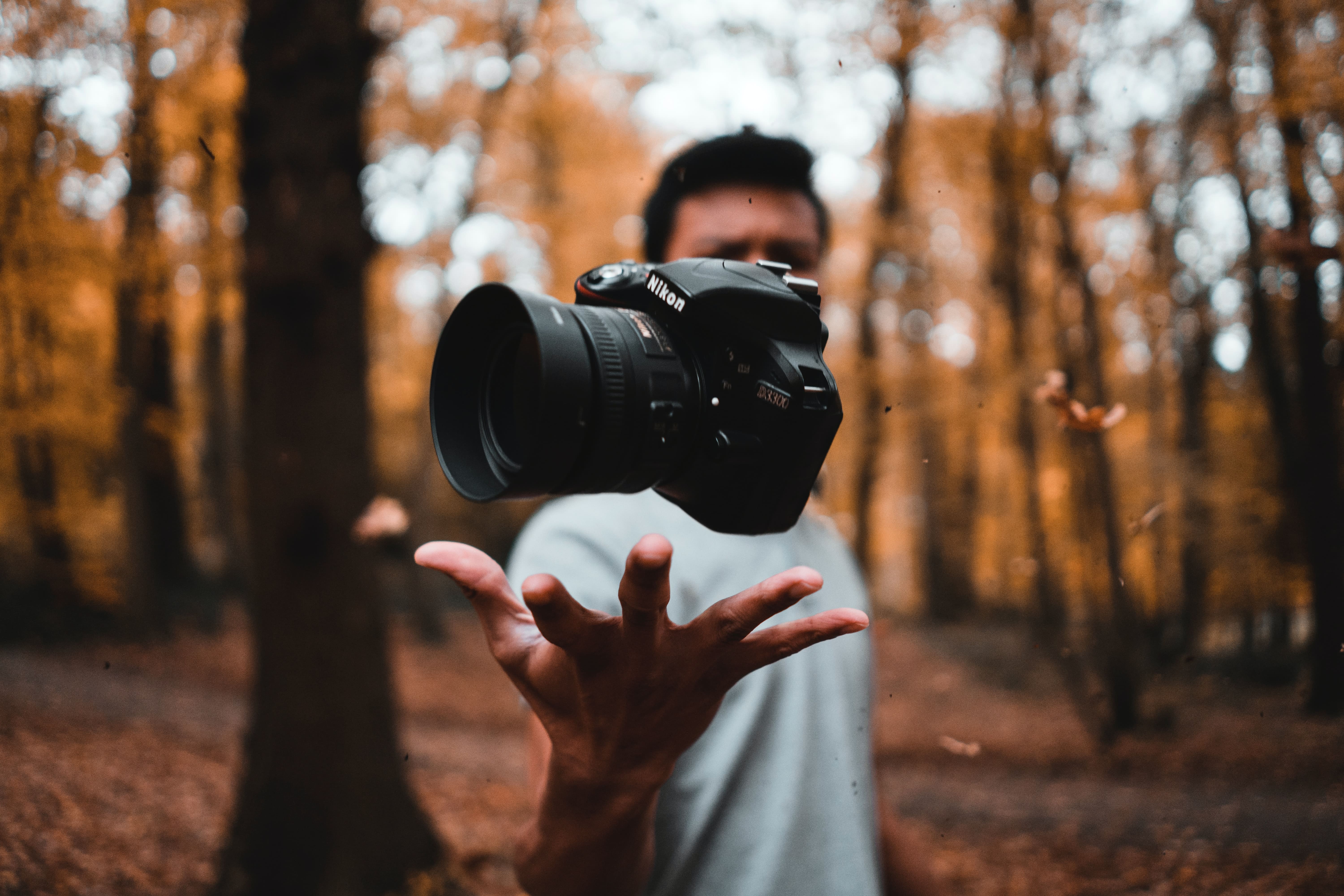 chico en el bosque lanzando su cámara, para el concurso de fotografía