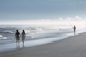 Personas paseando y pescando en una playa