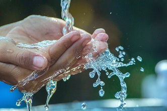 Unas manos de un hombre lavándose con agua. Medio Ambiente
