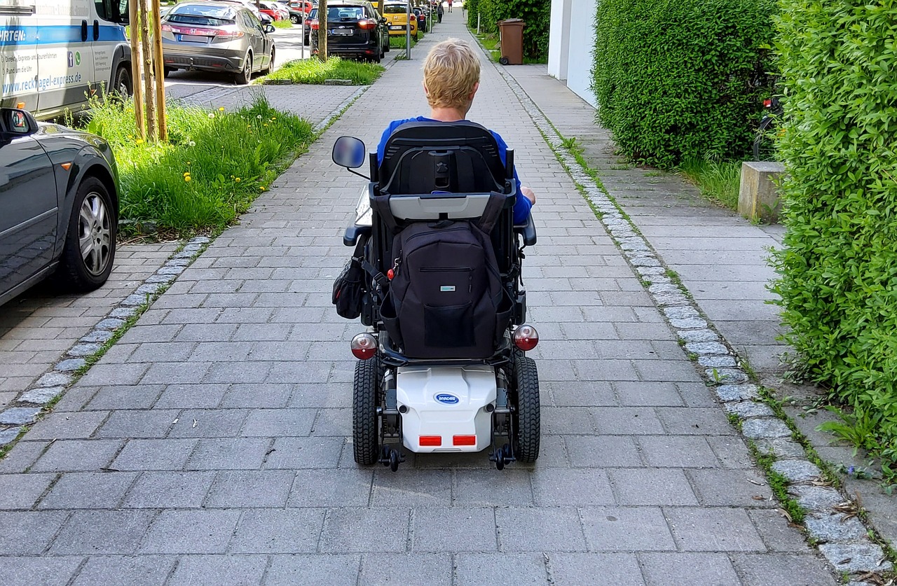 Persona en silla de ruedas por acera accesible
