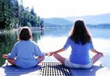 Una mujer y un niño haciendo yoga frente a un lago