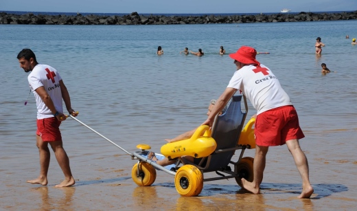 voluntarios de Cruz Roja ayudando a un bañista en un punto de baño del localizador de playas