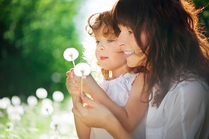 mama con su hija en el campo viendo flores diente de león