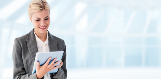 chica con traje sonriendo a ver en su tablet la oferta de trabajo