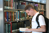 Estudiante en una biblioteca mirando la guía universitaria