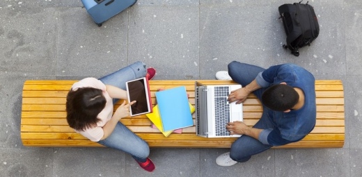 dos personas en un banco con sus portátiles viendo recursos de tecnología inclusiva