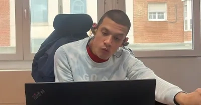 Kenjy trabajando en una oficina con su portatil