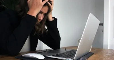 mujer con las manos en la cabeza mirando su pórtatil