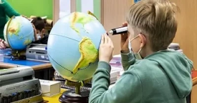 estudiante con una discapacidad visual, tocando un globo terráqueo