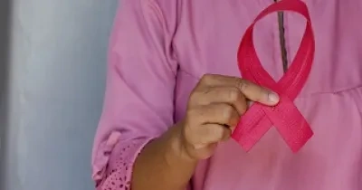 Mujer sujetando un lazo que simboliza el cáncer de mama