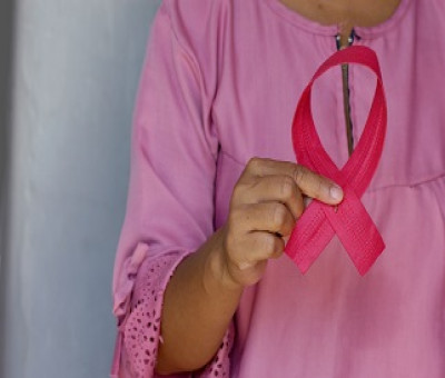 Mujer sujetando un lazo que simboliza el cáncer de mama