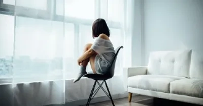 chica sentada en una silla mirando por la ventana