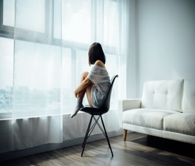chica sentada en una silla mirando por la ventana