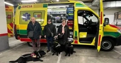 Imagen de tres personas con perros de asistencia en una ambulancia