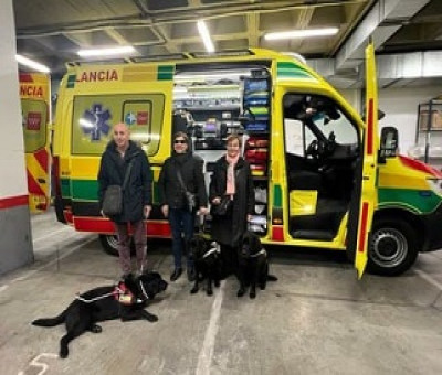Imagen de tres personas con perros de asistencia en una ambulancia